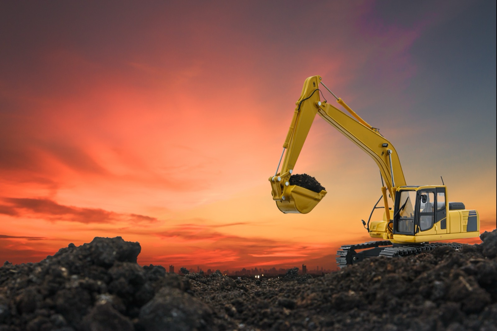 Excavator grading soil on a residential job site